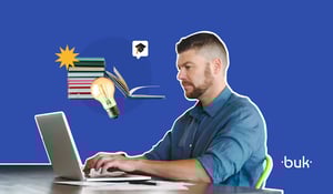 Homem concentrado usando notebook, com pilha de livros, lâmpada acesa e ícone de formatura ao fundo. Representa o desenvolvimento e treinamento de Hard Skills. Logo da Buk no canto inferior direito.