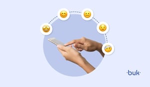 Mãos usando celular com emojis de sentimentos ilustram o que é pesquisa de clima organizacional, ferramenta de RH para medir satisfação e engajamento dos colaboradores.
