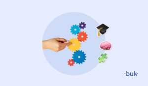 Imagem mostra uma mão mexendo em várias pequenas engrenagens coloridas. O fundo da imagem é azul claro e, ao lado dela, existem ícones de cérebro, um chapéu de formatura e uma peça de quebra-cabeça.